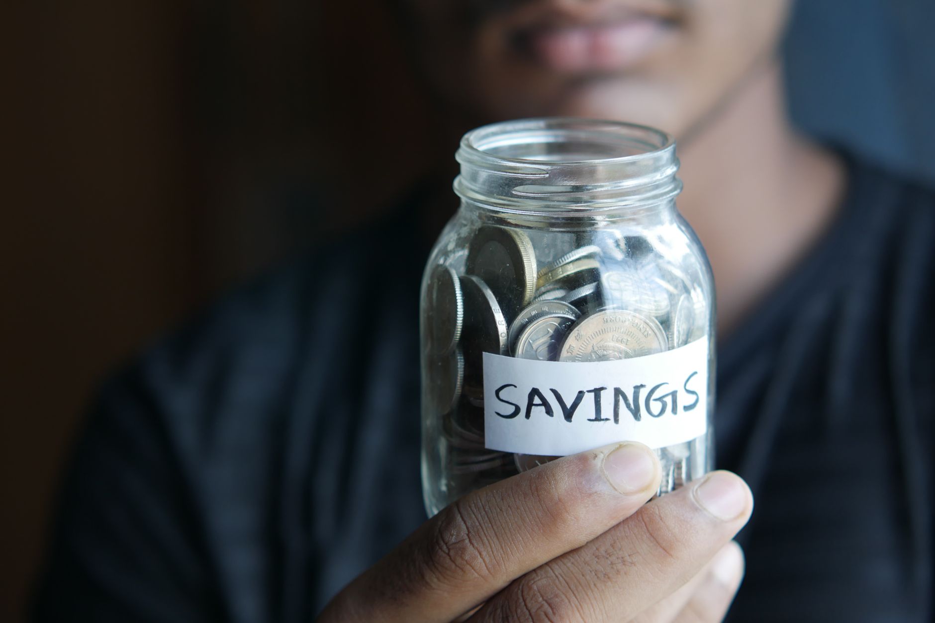 close up shot of a person holding a jar with coins