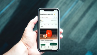 photo of a hand holding a phone with a delivery app on screen