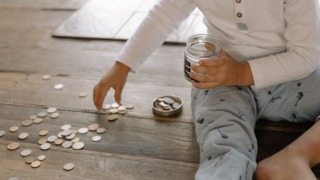 child putting coins into glass jar