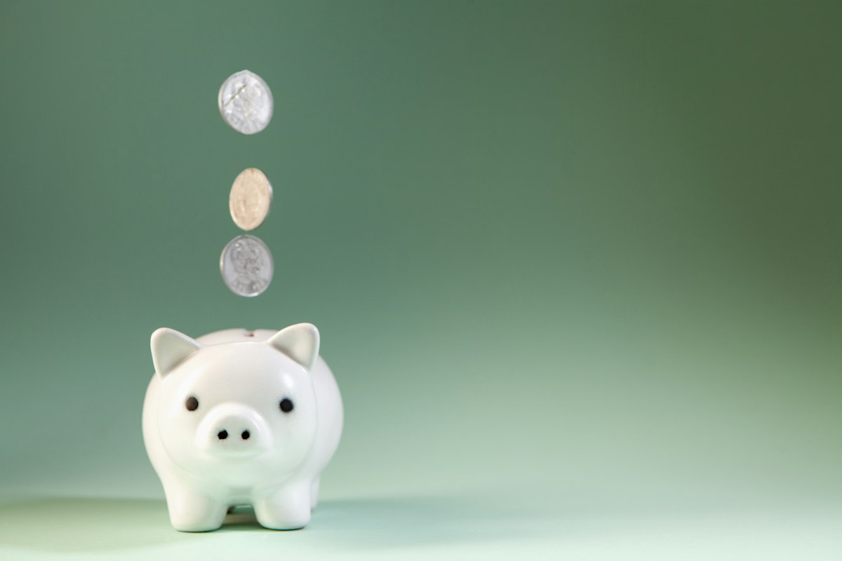 白い貯金箱と硬貨。家計と貯蓄を考えるイメージ